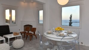 Un comedor moderno con una mesa redonda, sillas transparentes y vistas al mar a través de amplios ventanales.