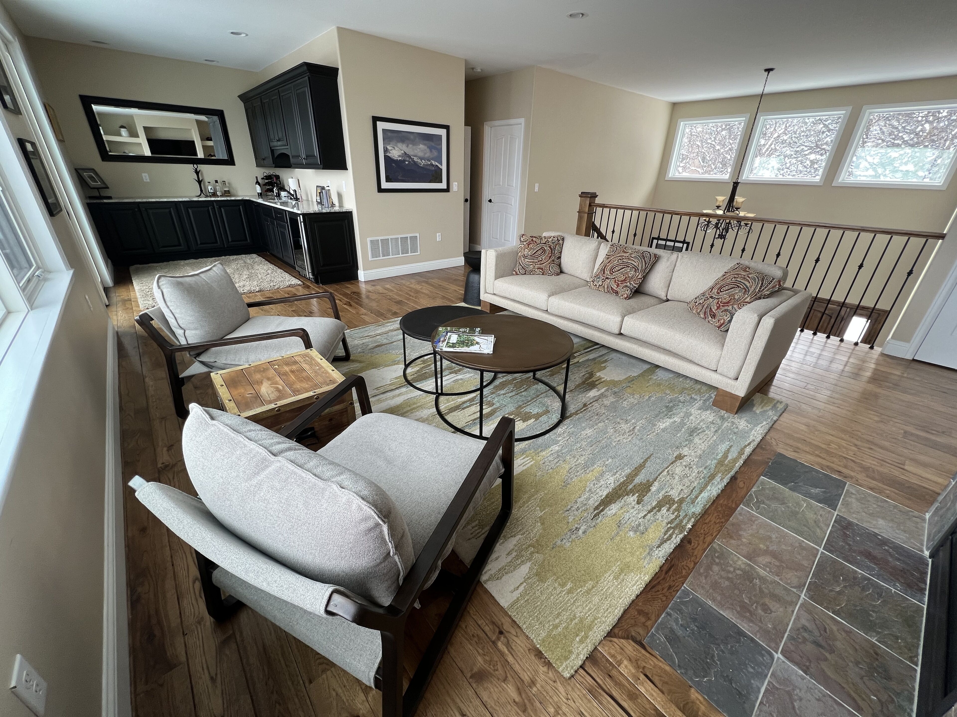 A spacious living room with a sofa, chairs, a coffee table, and a kitchen in the background.
