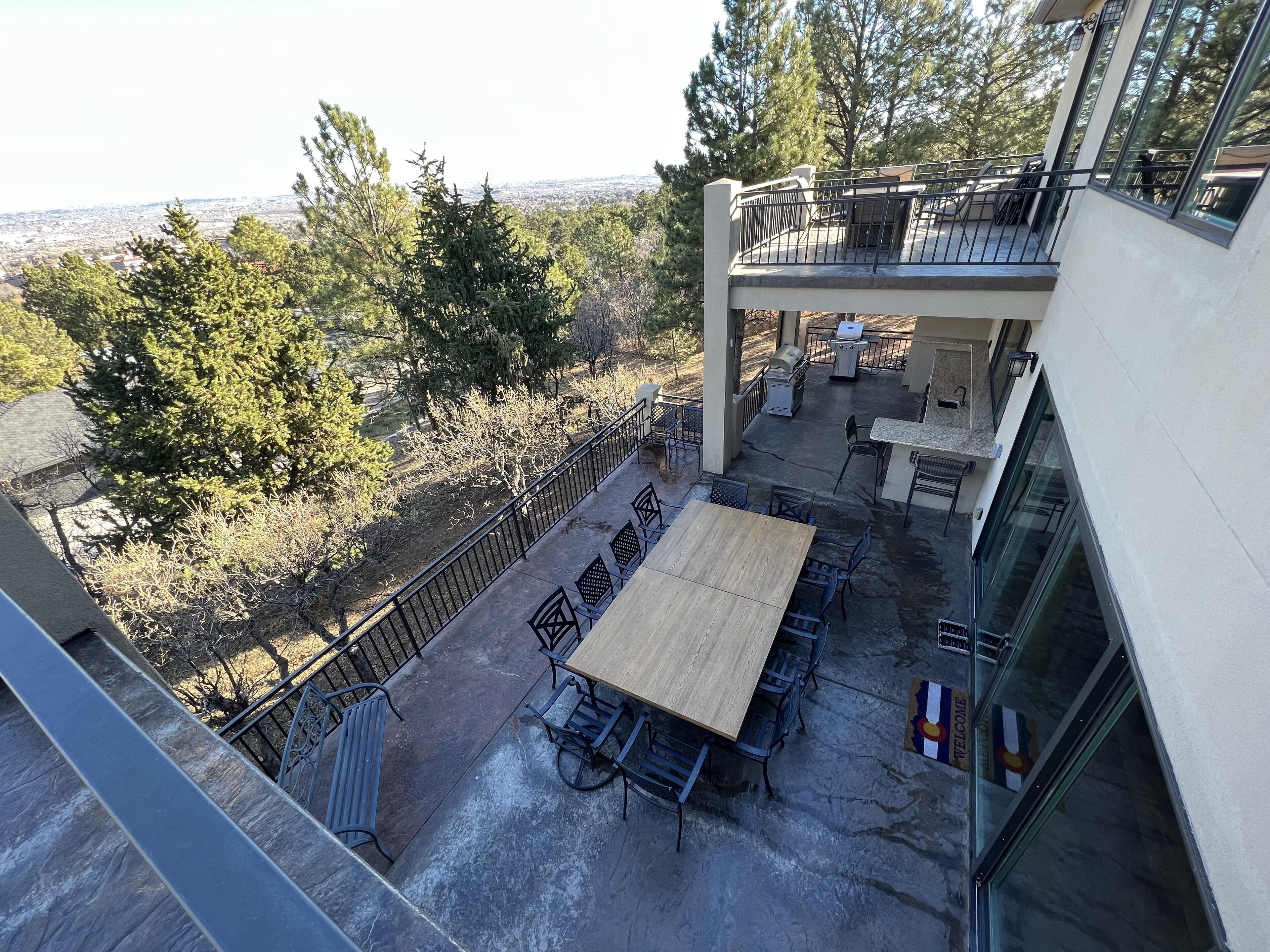 Une terrasse extérieure avec une grande table et des chaises, un barbecue et une vue sur le paysage urbain.