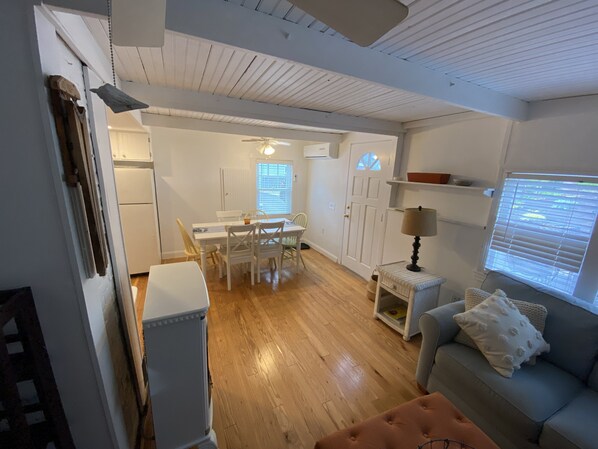 A spacious living area with a dining table, a sofa, and a small side table with a lamp.