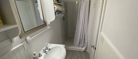 A bathroom with a white sink, mirror, and shower curtain.