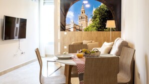 Une chambre d’hôtel moderne dotée d’un coin repas, d’un téléviseur à écran plat et d’une grande fenêtre offrant une vue sur le paysage urbain.