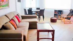 Una sala moderna con un sofá, una mesa de centro de vidrio y un comedor con sillas y una mesa.