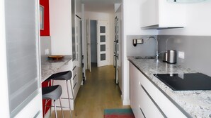 Una cocina moderna con encimera de mármol, pileta integrada y ventilador de techo.