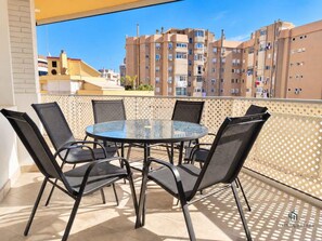 A balcony with a round glass table and six chairs, overlooking a residential area with apartment buildings. - Reding 8 Terrace Living4malaga (Málaga)