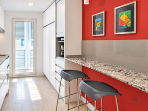 A kitchen with a red accent wall, two bar stools, and a countertop. - Reding 8 Terrace Living4malaga (Málaga)