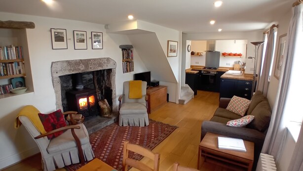 Una sala de estar acogedora con chimenea, un comedor y una cocina al fondo.