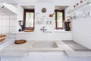Una cocina con un lavamanos amplio, una cafetera y una ventana con vistas a zonas verdes.