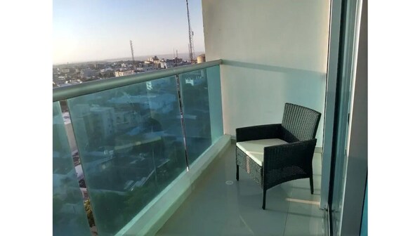 Enjoy the city view from this balcony with a glass railing and wicker chair.