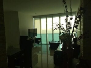 Relax in this stylish living room with a large flat-screen TV and sliding glass door leading to a balcony with a view.
