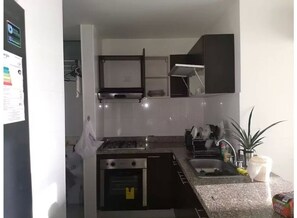 Compact kitchen with oven, stovetop, sink, and storage.