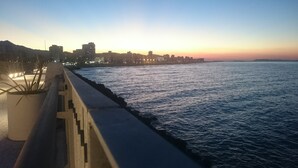 Paesaggio costiero al tramonto con una passeggiata che si affaccia sul mare.