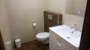 A small, modern bathroom with a toilet, sink, and trash can.