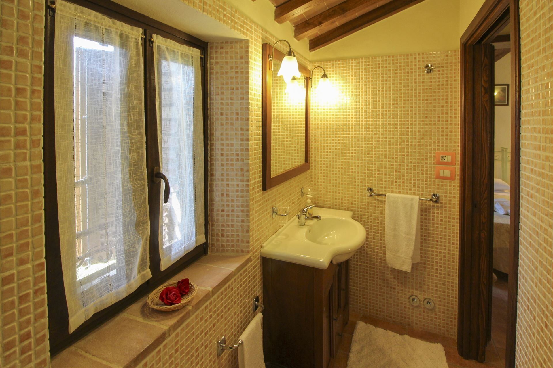 Een badkamer met een wastafel, spiegel en douchehoek.