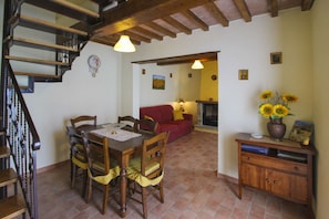 A dining area with a wooden table and chairs, a red sofa, and a fireplace. - Beautiful private villa for 7 people with private pool and TV (Città Di Castello)