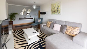 Una sala de estar moderna con un sofá gris, una mesa de centro blanca y un felpudo con estampado de cebra.