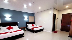 A hotel room with two beds, each with white bedding and red accents, a small bedside table, and a red mat on the floor. - Charms Hotel (Coron)
