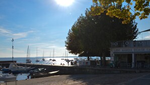 Un café frente a la playa con terraza, vista al mar y barcos amarrados cerca.