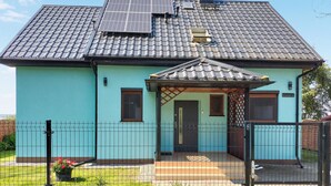 Ein Haus mit Ziegeldach, Solaranlage und umzäunter Garten.