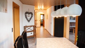 Un comedor con una mesa y sillas, techo de madera y un pasillo que conduce a otra habitación.