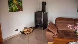 Una sala de estar con un sofá marrón, una chimenea y un cuadro de un bosque.