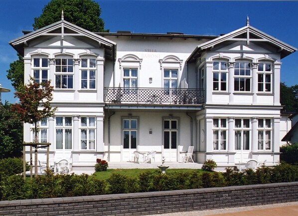 A large, two-story building with a balcony and multiple windows.