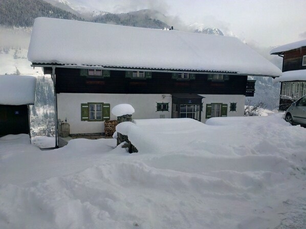 A two-story building with a snow-covered roof and a visible entrance. - Cozy cottage in a quiet location and wonderful views (Bad Gastein)