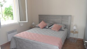 A bedroom with a bed, two bedside tables with lamps, a window, and a radiator. - Vaucluse- Pied du Ventoux- Le Barroux- Gravel house (Le Barroux)
