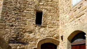 A stone building with a central arched doorway, two small windows, and a large window with shutters. - Vaucluse- Pied du Ventoux- Le Barroux- Gravel house (Le Barroux)