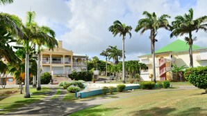 Un resort con un patio central, palmeras y un edificio con techo verde.