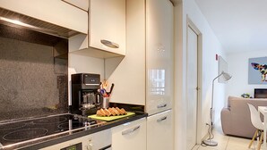 A modern kitchen with a black stove, white cabinets, and a coffee maker on the counter.