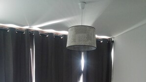 Un dormitorio con cama, almohadas, una mesita de noche y una lámpara colgante.