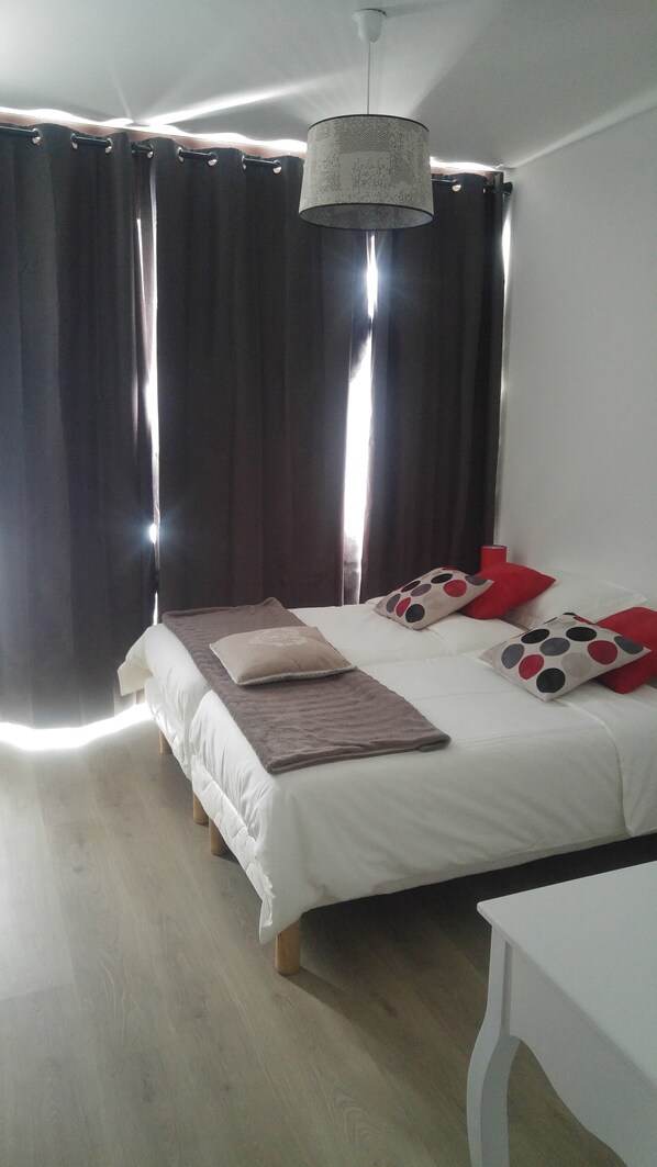 Ein Schlafzimmer mit einem Bett, Kissen, einem Nachttisch und einer Hängelampe.