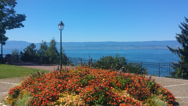 Una jardinera con un farol y vista a un cuerpo de agua y montañas distantes.