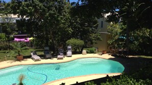 A swimming pool with lounge chairs and a small garden area. - Ouemoplage Araucaria independent studio in a villa (Magenta)