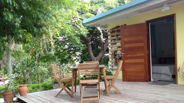 A wooden deck with a table and chairs, a wooden door, and a tree in the background. - Ouemoplage Araucaria independent studio in a villa (Magenta)