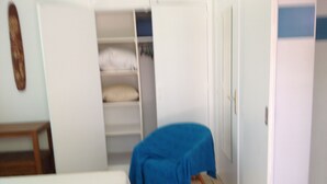 A bedroom with a bed, a small table, and a closet with shelves. - Ouemoplage Araucaria independent studio in a villa (Magenta)