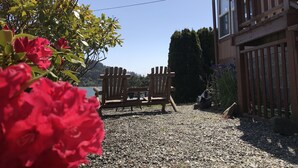 A gravel driveway leading to a wooden deck with two Adirondack chairs. - Where the river meets the beautiful Oregon Coastline. (Gold Beach)