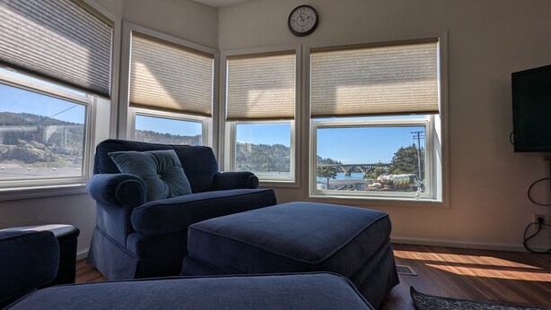 A room with a large window, a sofa, and a television. - Where the river meets the beautiful Oregon Coastline. (Gold Beach)