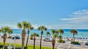 A coastal road with palm trees, a beach, and a clear blue sky. - Janie & Charlies Beach Escape
 2br 2 bath ,Beautiful view of the Gulf of Mexico. (Miramar Beach)