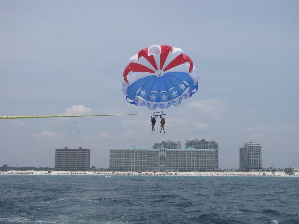 A parasailing activity over a body of water with buildings in the background.