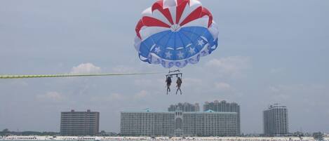 A parasailing activity over a body of water with buildings in the background.