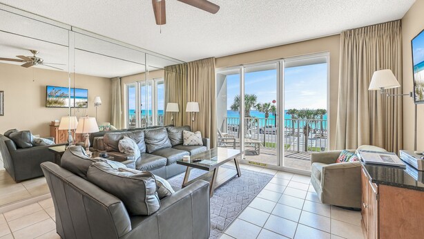 A spacious living room with a large sofa, a coffee table, and a view of the ocean through large sliding doors. - Janie & Charlies Beach Escape
 2br 2 bath ,Beautiful view of the Gulf of Mexico. (Miramar Beach)