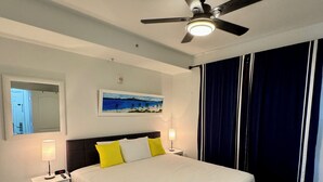 A neatly arranged bedroom with a bed, bedside tables, a ceiling fan, and a painting on the wall. - New! 1-King Bedroom, 2 baths with Breathtaking view at Blue Heron Beach Resort (Orlando)
