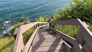 Una escalera de madera que desciende a una playa con aguas azules y transparentes.