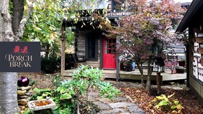 Experience the charm of a rustic cabin with a welcoming red door, surrounded by a beautifully maintained garden and a stone pathway.