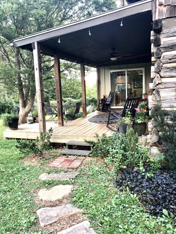 Relax in a shaded outdoor space with a deck, chairs, and table, surrounded by lush vegetation.