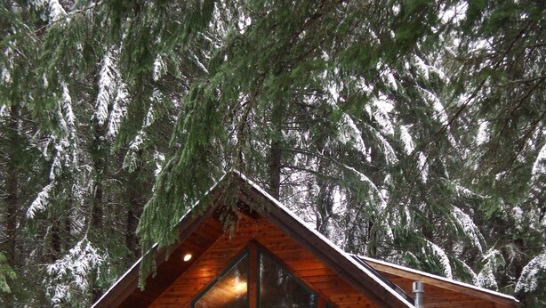 A wooden cabin with large windows, a porch, and a snow-covered ground. - Greenwater chalet/cabin - 3 bed + loft - 2 full baths (Enumclaw)