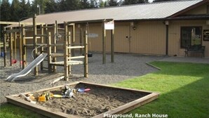 A playground with a slide and climbing structures, a sandbox, and a building with a metal roof. - Greenwater chalet/cabin - 3 bed + loft - 2 full baths (Enumclaw)