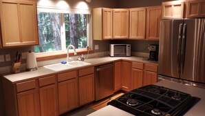 A modern kitchen with wooden cabinets, a stainless steel refrigerator, a microwave, and a gas stove. - Greenwater chalet/cabin - 3 bed + loft - 2 full baths (Enumclaw)